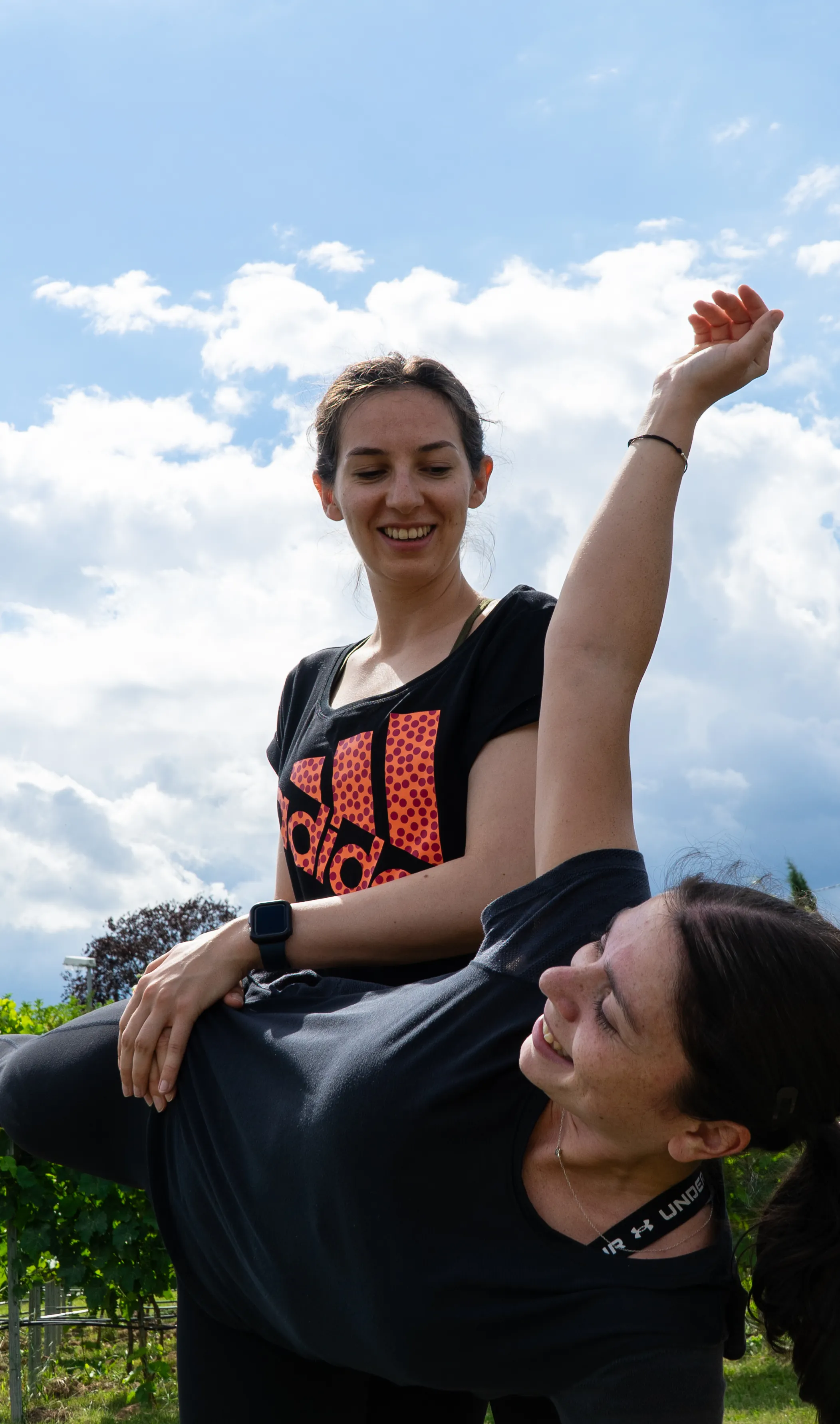 Zwei Teilnehmerinnen unterstützen sich beim Power Yoga im Weingut in Worms